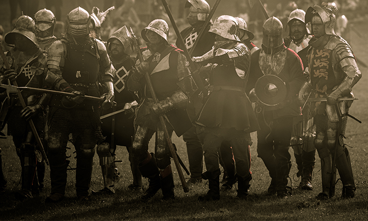 A group of re-enactors in armour prepare to fight in the mist